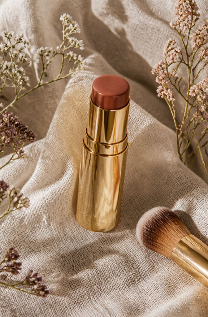 Brown Blush Makeup: 20 Best Picks for 2026 18 Merit Flush Balm in Terracotta displayed with muted wildflowers.