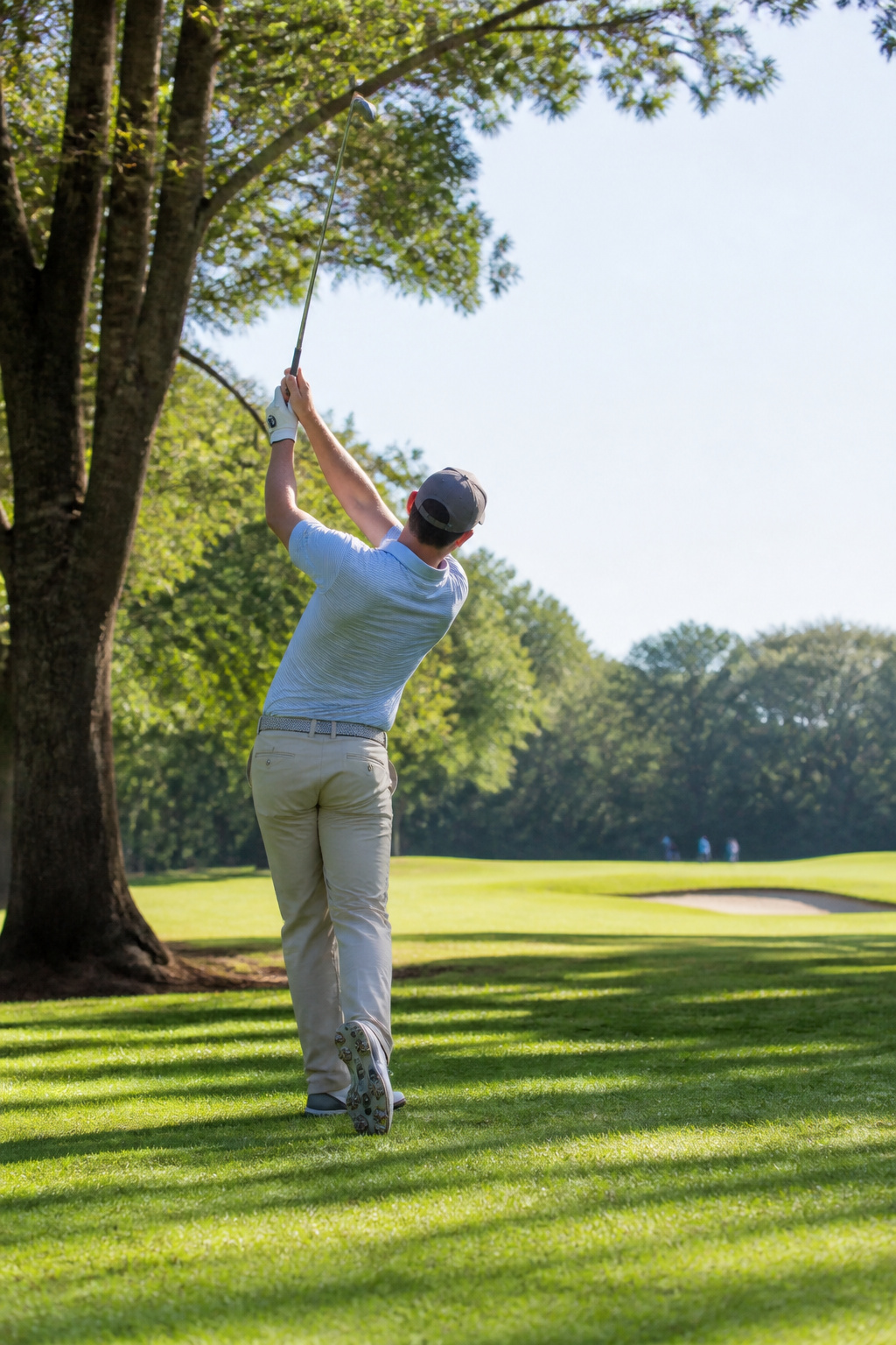 Golfer finishes swing with left arm extended high.
