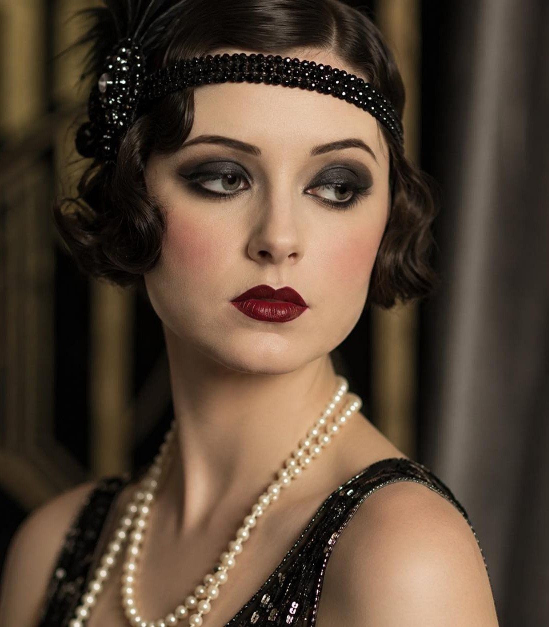 Woman with 1920s makeup featuring red cupid's bow lips and smoky eyes.