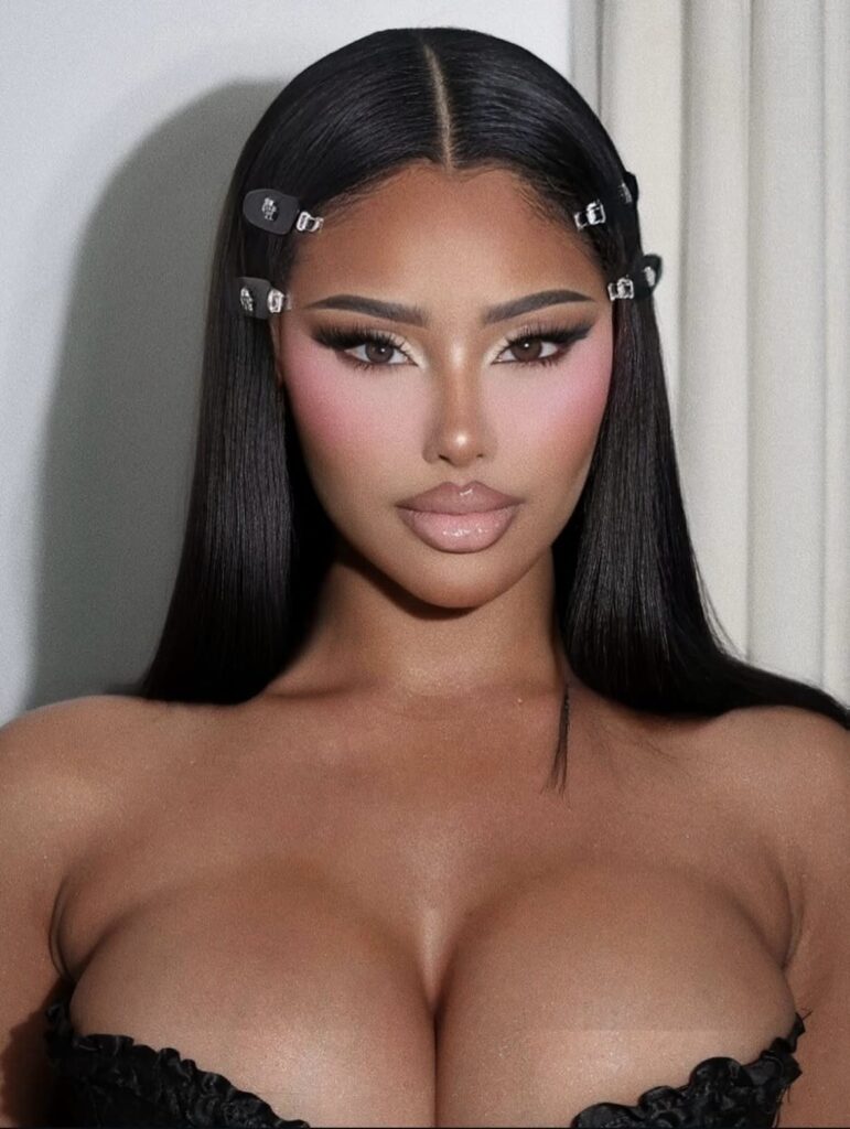 Woman with full glam makeup featuring contoured cheeks and glossy nude lips.