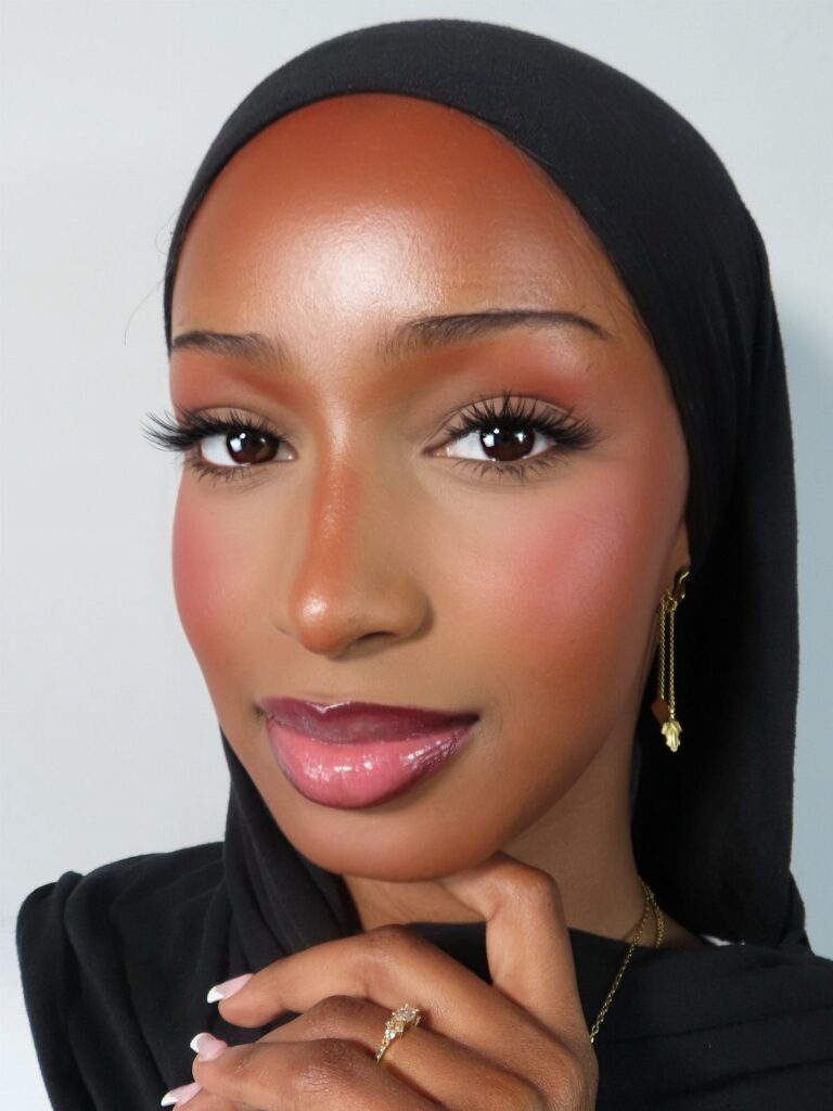 Woman with dark skin wearing a black hijab and long false eyelashes.
