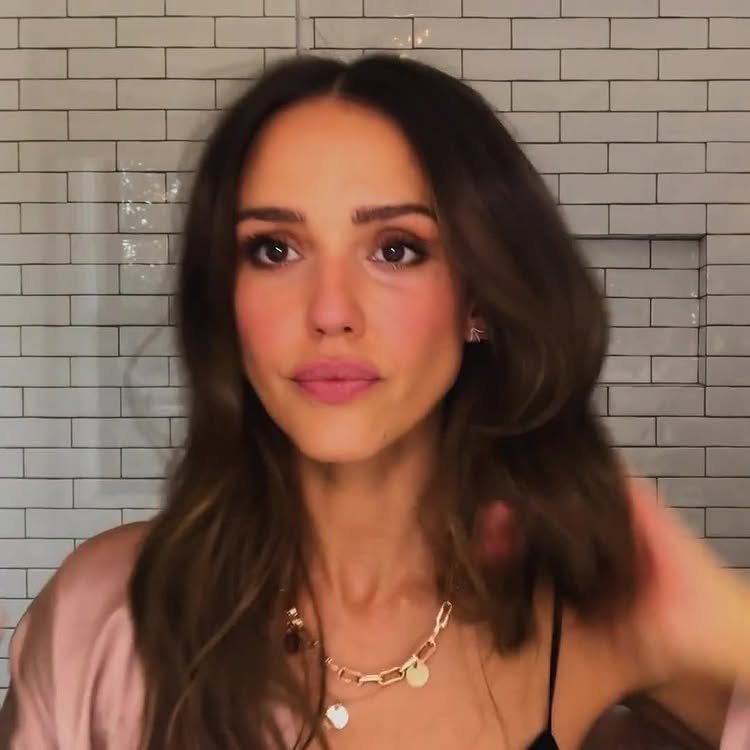Woman with brown hair wearing a smokey eye makeup look and gold jewelry.
