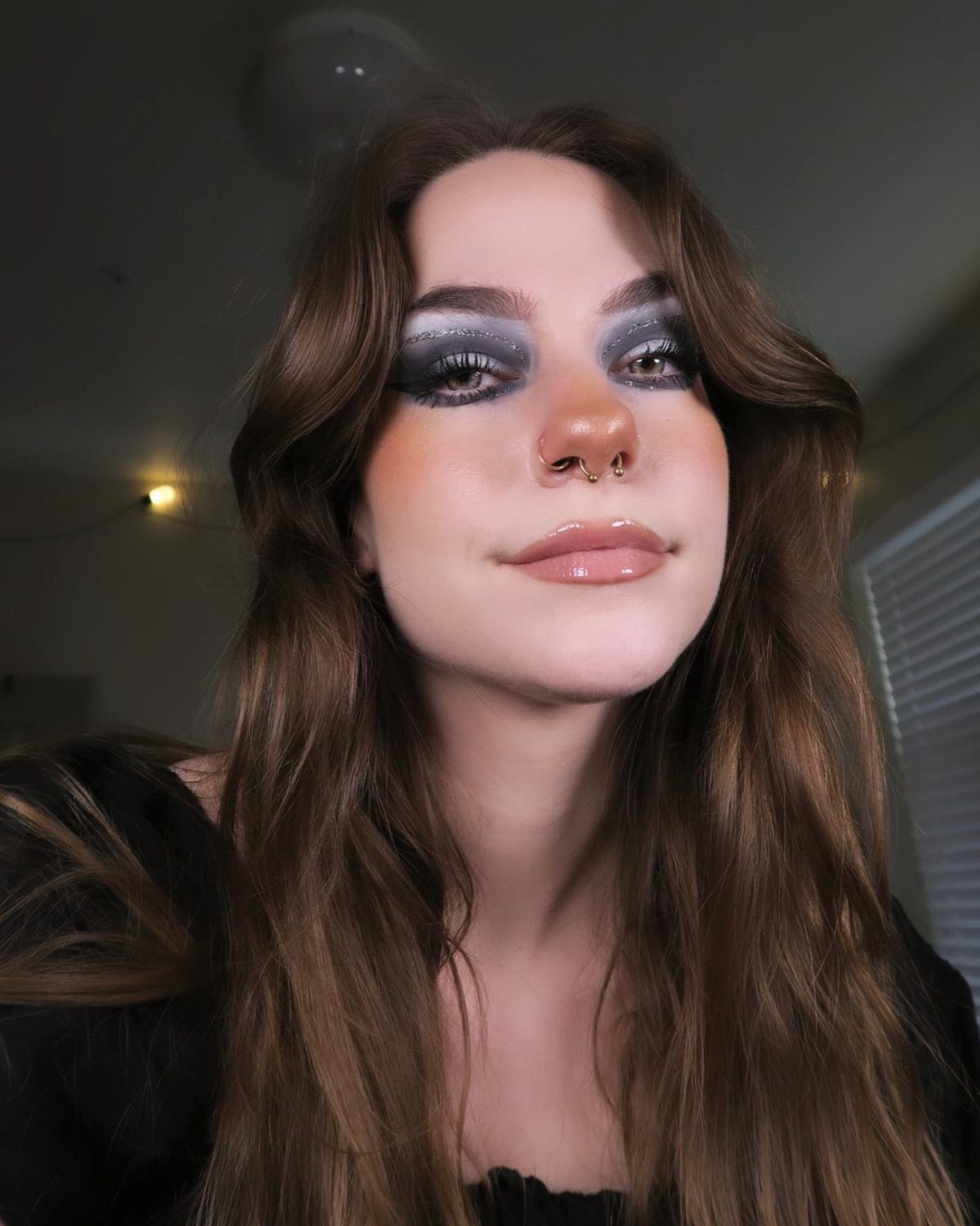 Woman with dark smoky eye makeup and subtle pink blush on her cheeks.