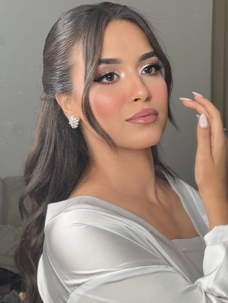 Woman with elegant makeup, shimmering eyeshadow, and nude lips wearing a white satin robe.