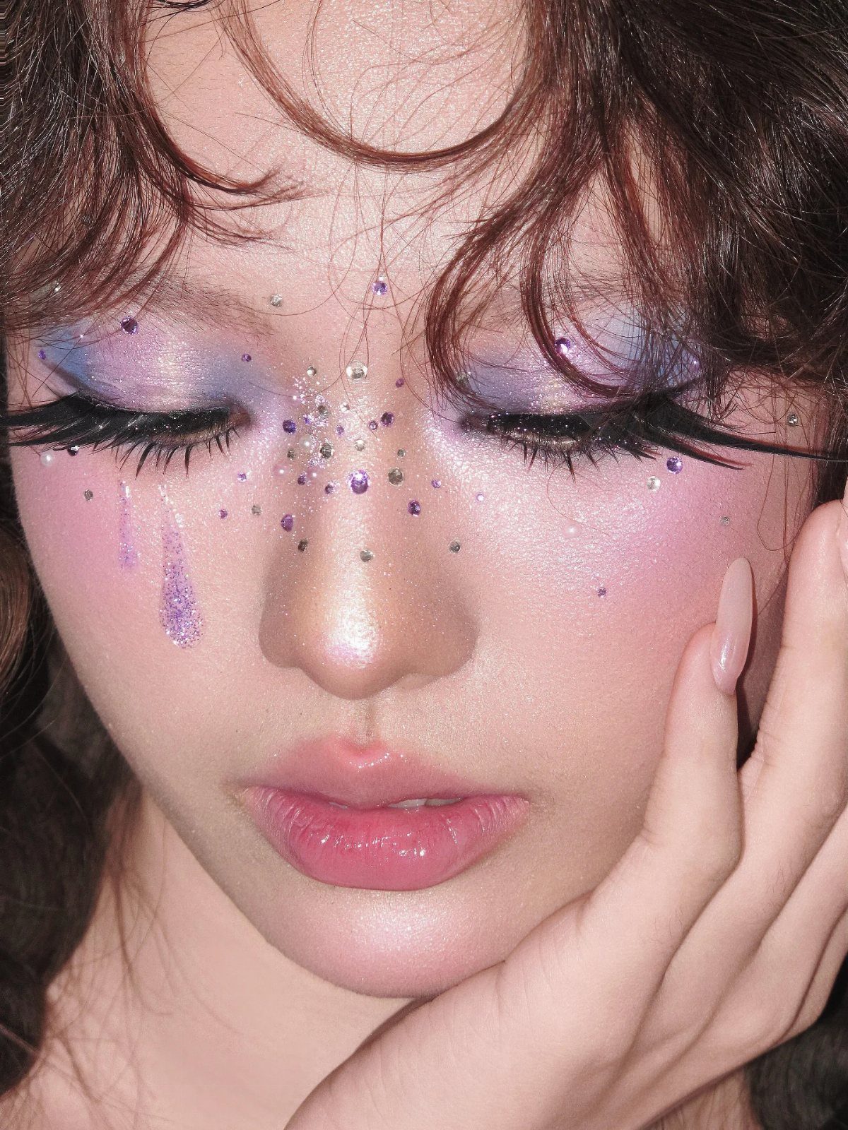 Person with shimmering purple and blue aura makeup and glitter on their face