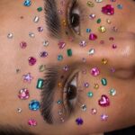Colorful rhinestones and gems applied around the eyes and eyebrows of a person