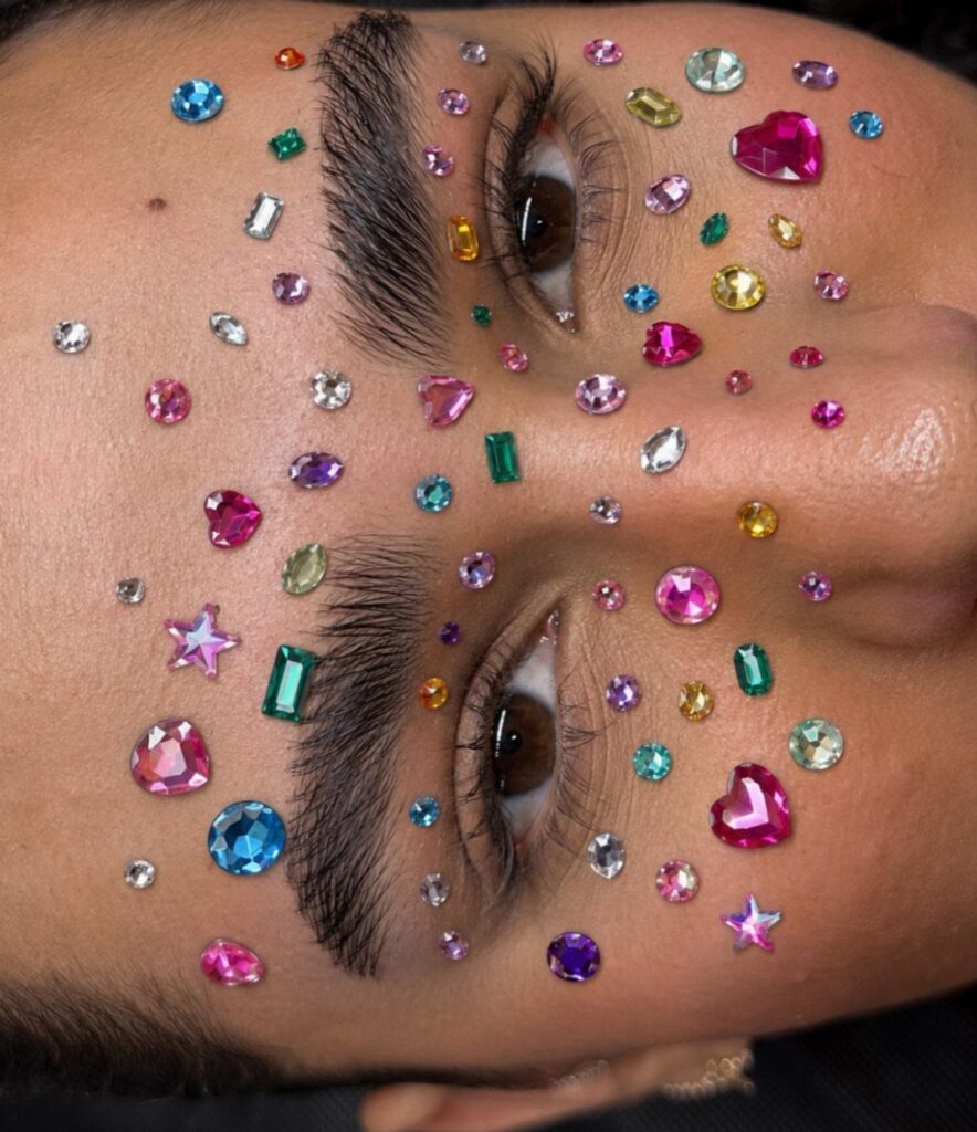 Colorful rhinestones and gems applied around the eyes and eyebrows of a person
