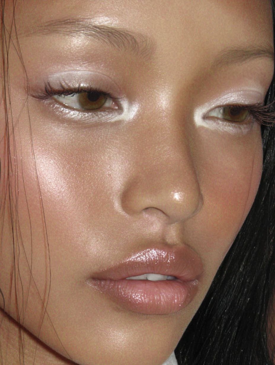 Person with shimmering light-colored eyeshadow on eyelids and glossy lips.