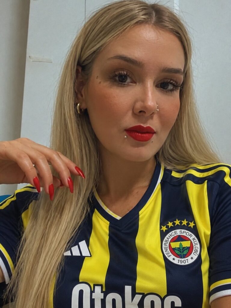 Woman in football jersey with bold matte red lipstick and matching red nails.