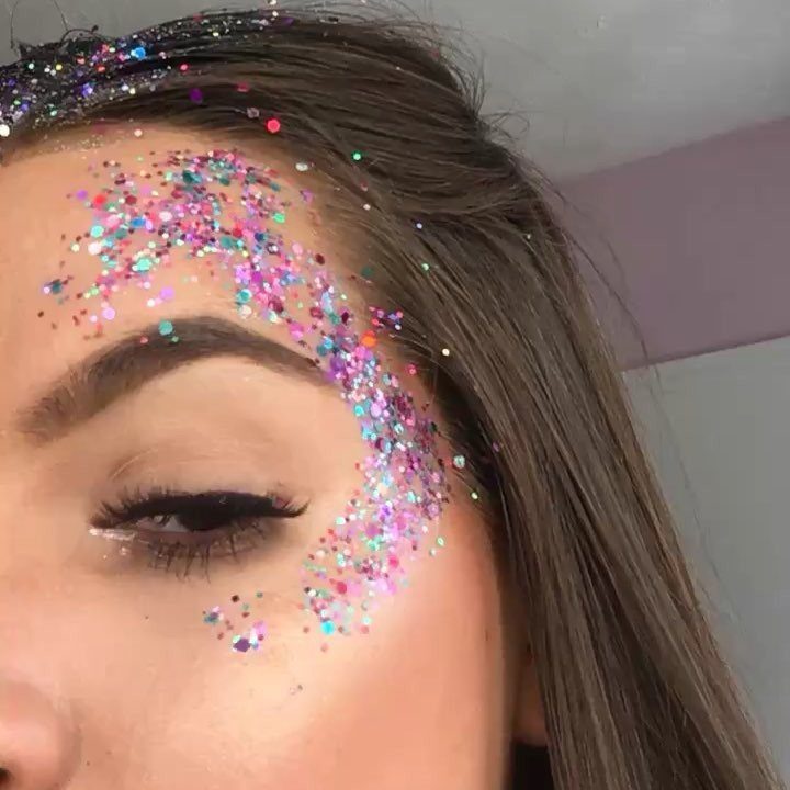 Person with colorful iridescent glitter applied around their eye and eyebrow area