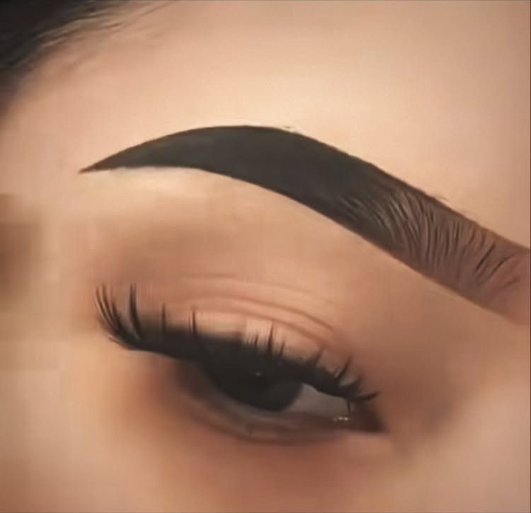 Defined dark brown eyebrow and long eyelashes on a person's face.