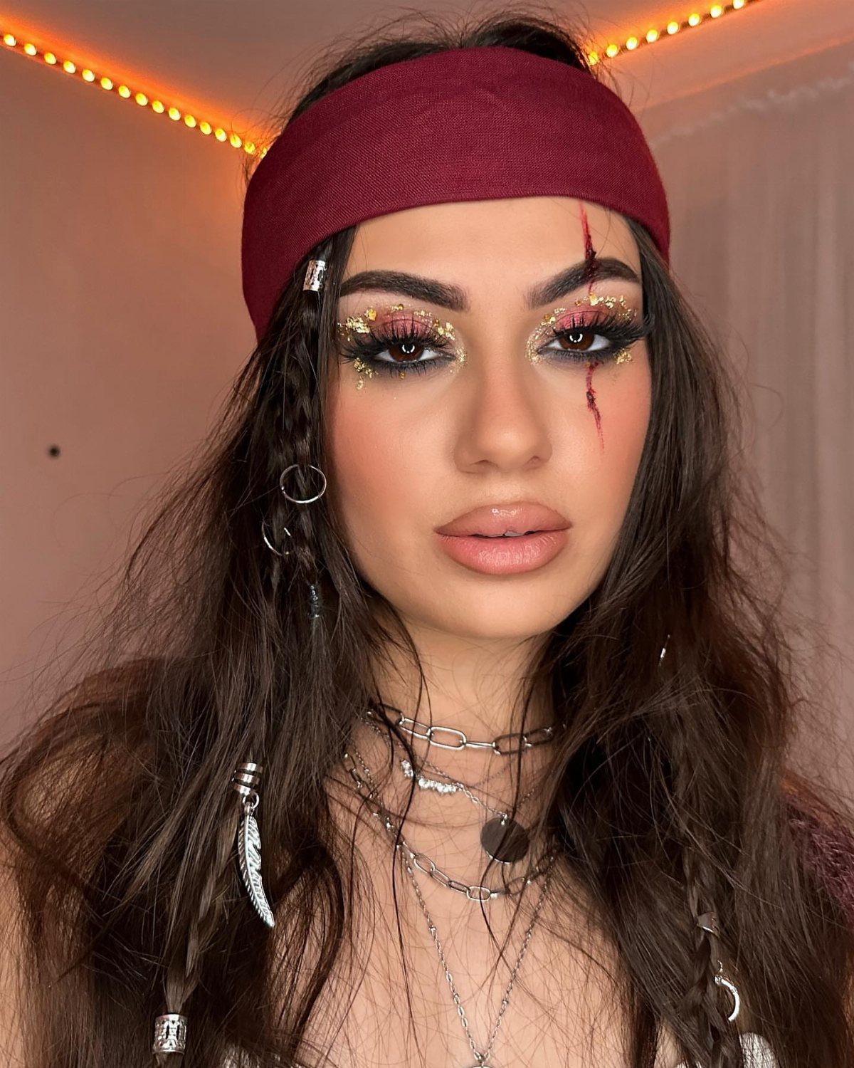 Woman with pirate makeup featuring gold glitter and a fake blood scratch.