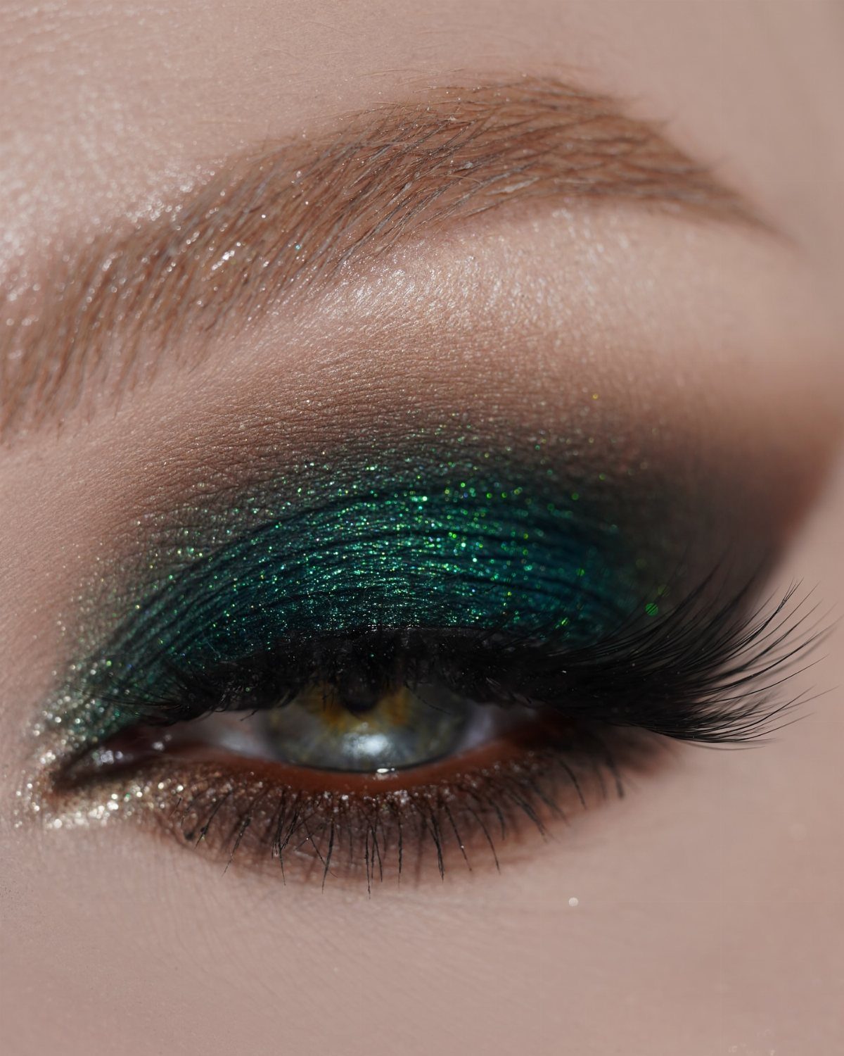 Close-up of an eye with shimmering emerald green smoky eyeshadow and long lashes.