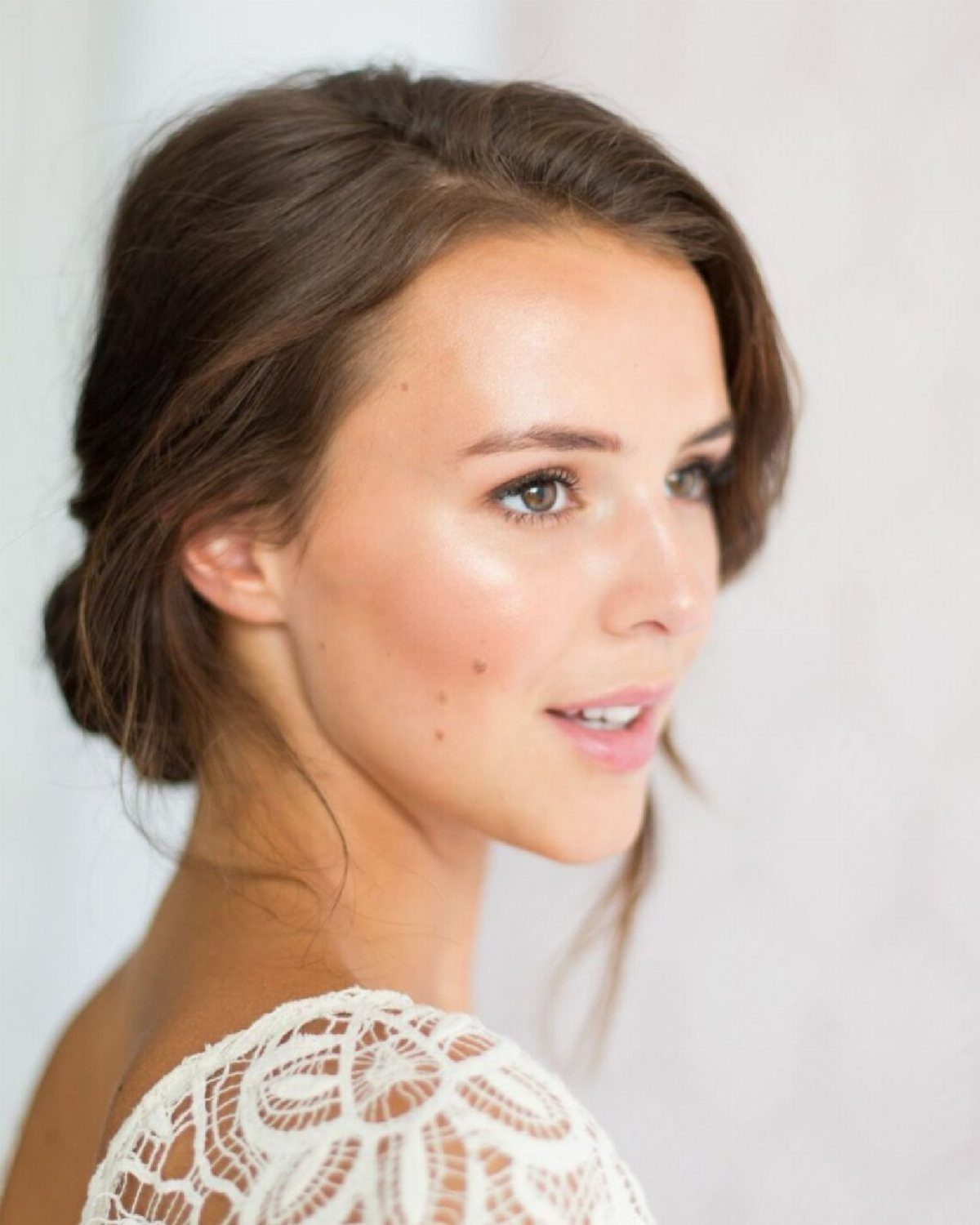 Woman with brown eyes wearing natural makeup and a white lace dress.