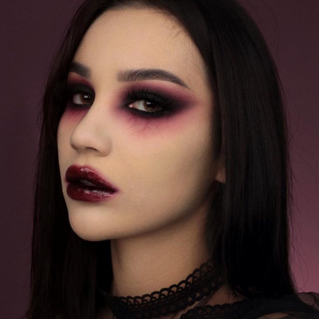 Woman with dark red and black vampire eye makeup and burgundy lips.