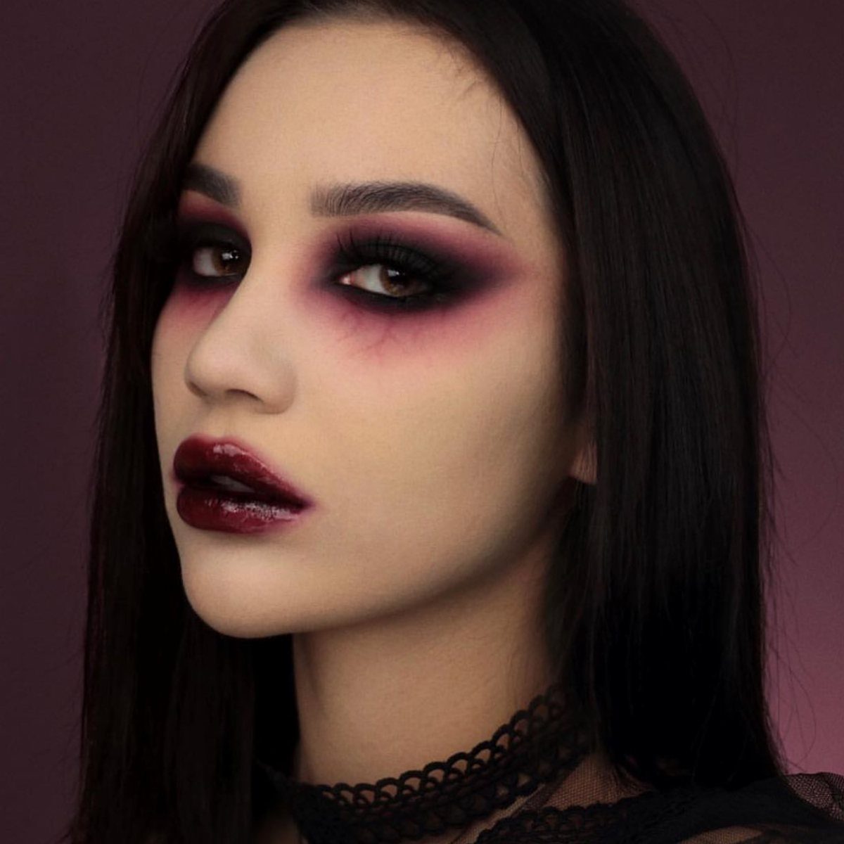 Woman with dark red and black vampire eye makeup and burgundy lips.