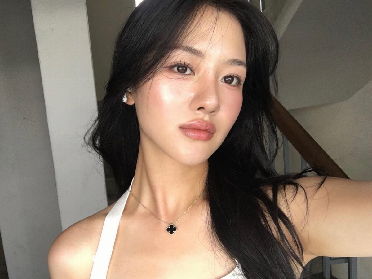 Woman with glowing skin and peach-tinted highlighter on her cheeks and nose.